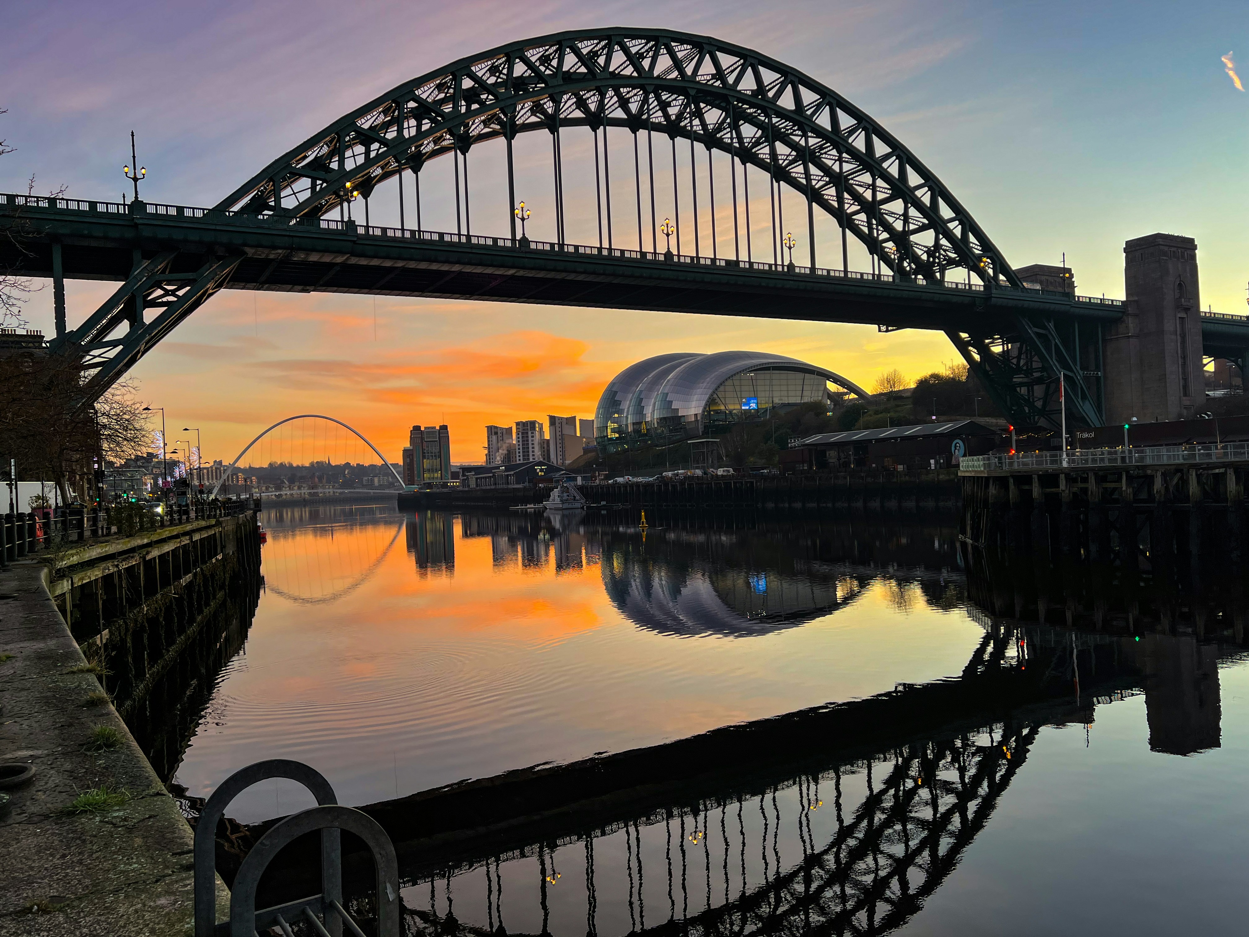 Newcastle Quayside at sunset — the Tyne Bridge reflected in the river